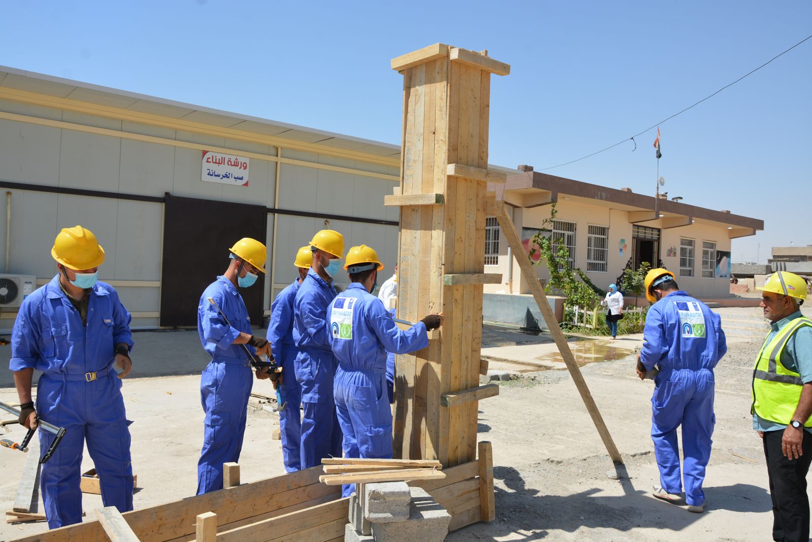 Trainees in hard hats practising formwork during vocational training