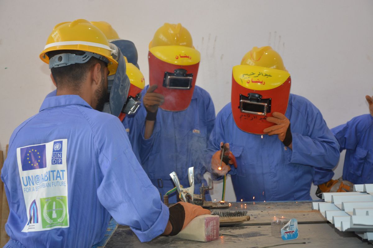 Trainees in welding masks practising during vocational training